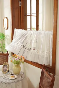 Détail de rideau court en dentelle vintage française, store de cuisine blanc style rétro.