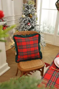 Detailed view of Christmas red plaid cushion cover with green ruffled edge for holiday home decor.