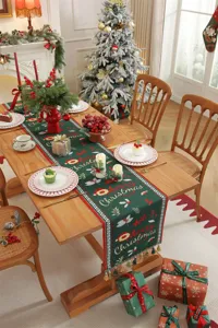 Vista dettagliata del runner da tavola natalizio verde con motivi jacquard e nappe eleganti.
