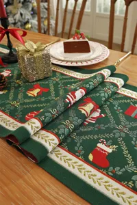 Dettaglio di runner da tavola natalizio in jacquard con motivi festivi su verde.