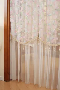 Delicate French style floral lace sheer curtain detail with embroidered flowers and hanging beads.