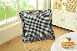 Detailed view of a black and white gingham throw pillow with elegant ruffled edge design.