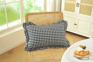 Close-up detail of black white plaid throw pillow with elegant ruffles for cozy room decor.