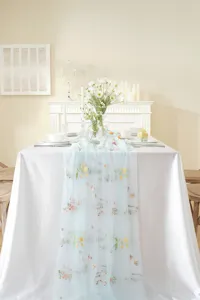 Detailed view of the sheer light blue table runner with colorful floral embroidery for dining.