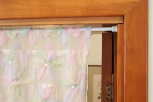 Close-up detail of the French style floral lace door curtain with pastel petals and sequins.