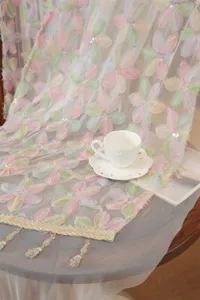 Close-up detail of French style embroidered floral lace gauze fabric with delicate bead fringe.