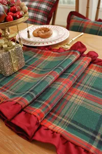 Close-up detail of Christmas plaid table runner with red ruffled edge, festive dining table setup
