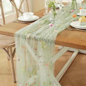Vintage green mesh table runner with colorful floral embroidery, ideal for elegant wedding decor.
