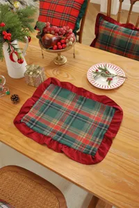 Detailed view of the Christmas plaid table mat with red ruffled edge on wooden table.
