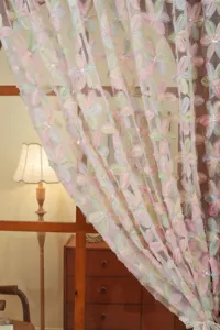 Close-up detail of French style pastel floral embroidered lace gauze curtain, elegant design.