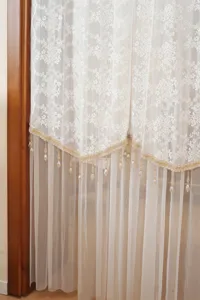 Detailed view of French style double layer lace door curtain with exquisite beaded fringe trim.
