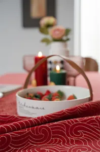 Detailed close-up of festive red and gold jacquard tablecloth showing delicate holiday pattern.