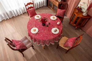 Vue détaillée de la nappe ronde jacquard rouge festive avec des motifs dorés élégants.