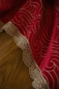 Red gold jacquard fabric tablecloth detail with luxury lace edge for festive wedding decor.