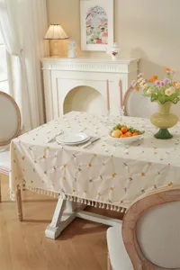 Elegante beige katoenen tafelkleed met gele bloemenborduursel en franjes voor de eettafel.