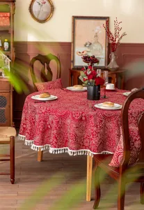 Nappe ronde rouge festive en jacquard avec motif floral blanc et jolie bordure de franges.