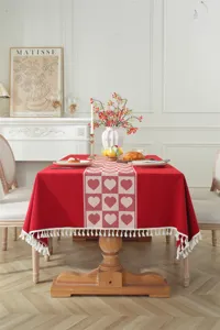 Detalle de mantel de jacquard rojo con patrón de corazones y borde de borlas blancas