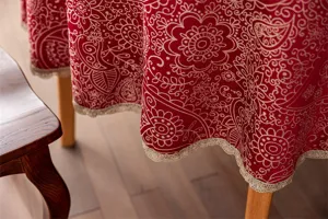 Détail de la nappe en jacquard rouge avec une belle bordure en dentelle dorée et des motifs.
