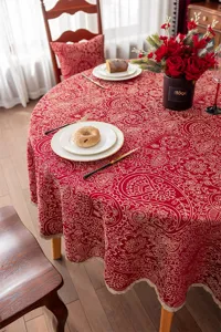Nappe ronde rouge en jacquard avec bordure en dentelle dores pour decoration festive.