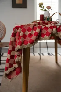 Red and beige checkered tablecloth with gold lace trim, festive dining table cover for home decor.
