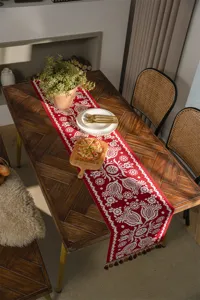 Red table runner with white floral jacquard patterns and elegant tassels for dining room.