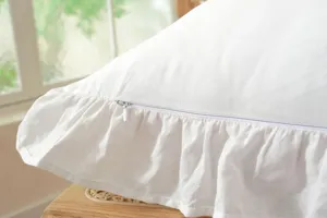 Fodera per cuscino bianca in cotone con volant e zip nascosta, dettaglio elegante per casa.