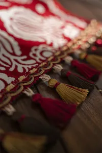 Close-up detail of the red jacquard table runner showcasing exquisite golden fringe tassels and texture.