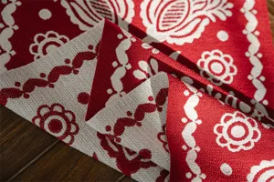 Detail shot of red and white jacquard table runner with geometric floral pattern for festive decor.
