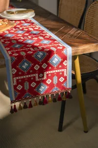Detailed close-up view of red geometric jacquard table runner with decorative tassels.