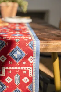 Detailed view of red geometric jacquard table runner showcasing delicate woven texture and blue border.