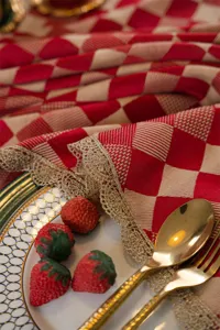 Red checkered tablecloth detail view featuring elegant gold lace trim and festive table decor.