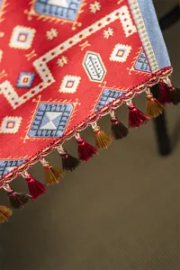 Close-up of red geometric jacquard table runner with exquisite tassels and details.