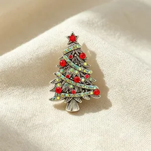 Close-up detail of vintage alloy Christmas tree brooch with red and iridescent rhinestones.
