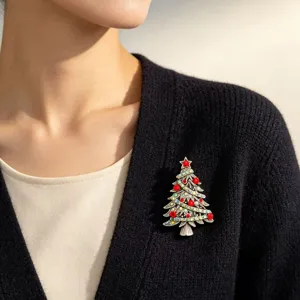 Close up of vintage crystal Christmas tree brooch pinned on elegant black knit cardigan.