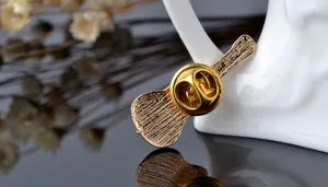 Detailed view of the gold metal guitar brooch back with secure pin clasp for apparel.