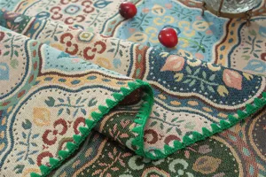Vue détaillée de la nappe jacquard avec motifs floraux et jolie bordure en dentelle verte.