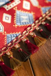 Close-up detail of the red decorative table runner featuring tassels and jacquard.