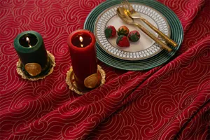 Detail shot of festive red waterproof jacquard round tablecloth with elegant gold swirl pattern.