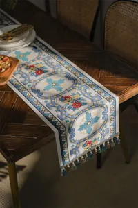 Jacquard table runner with blue geometric floral pattern and tassels for dining room decor.