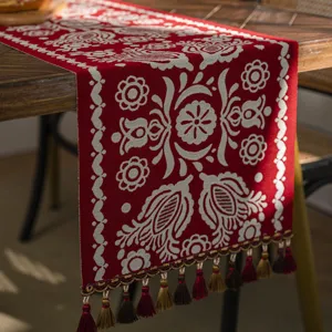 Red festive jacquard table runner with white ethnic floral pattern and tassels for dining table.