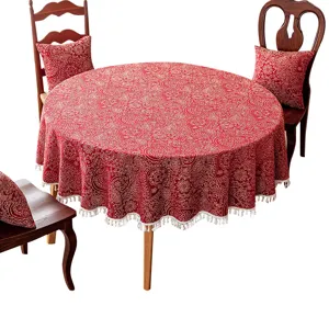 Nappe de table ronde festive rouge avec motif jacquard traditionnel et bordure frangée.