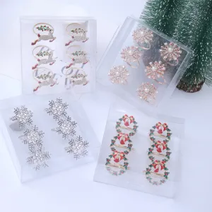 Close-up detail of assorted Christmas napkin rings in clear boxes, featuring festive designs.