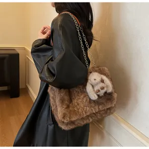 Close-up detail of fluffy brown plush shoulder bag with gold chain and cute bunny charm.