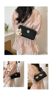 Elegant black leather shoulder bag with chic metal lock and cute plush pendant detail.