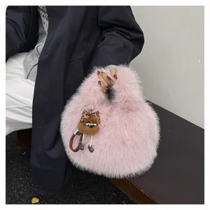Close-up of fluffy pink plush handbag detailed with a cute leopard bow charm for women.