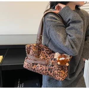 Detail view of the winter vintage suede leopard shoulder bag with brown strap and plush charm.