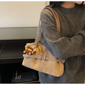Detailed view of winter vintage suede shoulder bag worn on shoulder with cute charm.