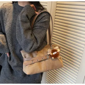 Suede underarm shoulder bag with belt detail and cute plush charm for women winter daily commute.