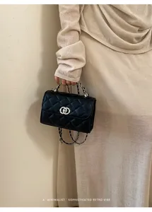 Black quilted handbag detail with chain handle and classic turn-lock closure design.