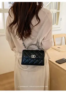 Detail shot of black quilted chain shoulder bag, stylish retro design with metal strap.